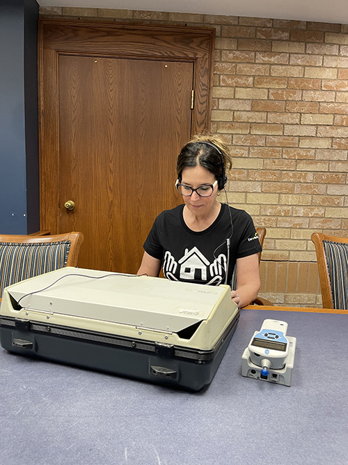 Juliana in front of hearing test and verification machine